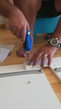 Man assembling flat-pack furniture with electric screwdriver