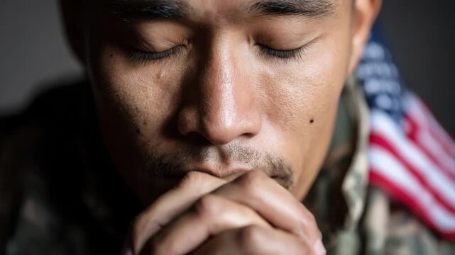 Slow motion static close up of soldier praying with american flag on uniform in indoor barracks portrait