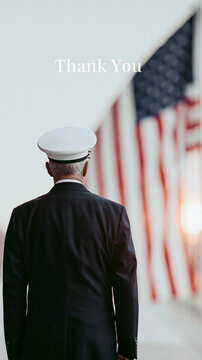 Male military officer in formal uniform stands with back to camera, facing large American flag, sunset light illuminating the scene, conveying respect and gratitude