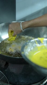 Vertical video close up of chef pouring hot clear broth with ladle over steamed momos in bowl