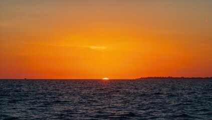 Fototapeta premium Sunset Over Calm Ocean Waters with Silhouette of Distant Shoreline