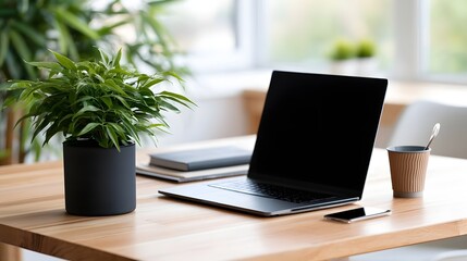 Fototapeta premium A minimalist wooden desk setup featuring a laptop potted plant notebook and coffee cup under soft natural light