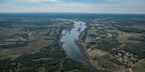 Fototapeta premium Aerial View of Meandering River Surrounded by Lush Green Fields under Clear Blue Sky
