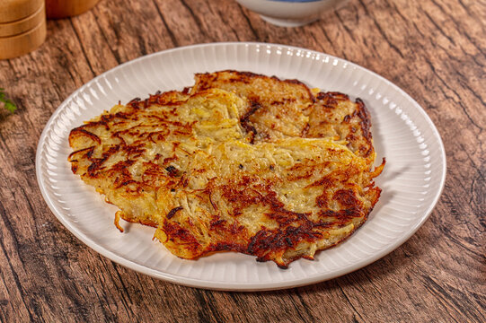 Crispy golden hash brown on white plate over rustic wooden table