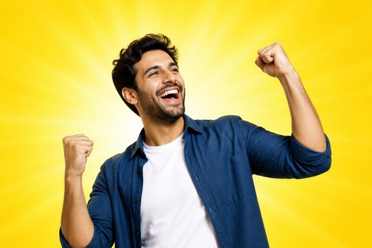 Man celebrating with raised fists on yellow background