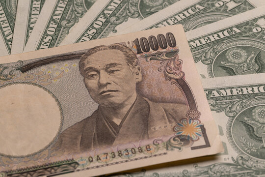 Japanese 10000 yen banknote with portrait over fanned US dollar bills background