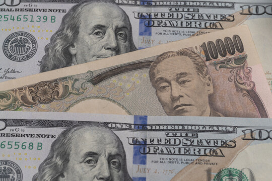 Japanese 10000 yen banknote placed between US 100 dollar bills