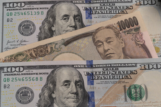 Japanese 10000 yen banknote placed between US 100 dollar bills