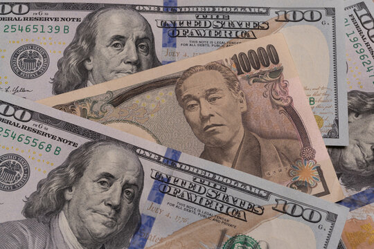 Japanese 10000 yen banknote placed between US 100 dollar bills