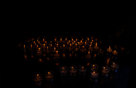Burning Prayer Candles in Dark Church Interior for Faith, Remembrance and Spiritual Reflection