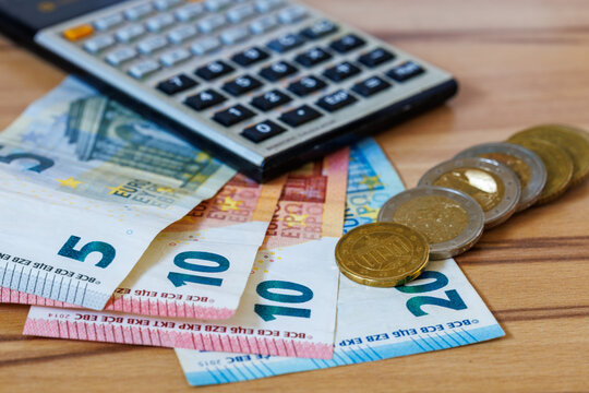Euro banknotes, coins and calculator on wooden table for personal finance, budgeting and accounting
