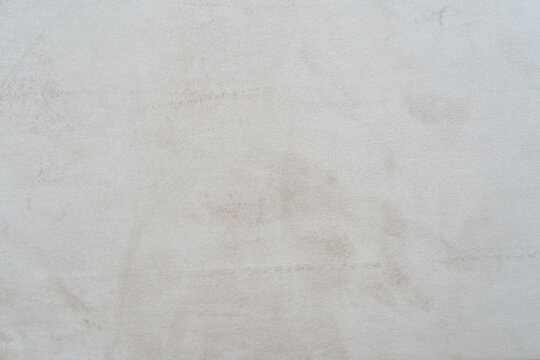 Full-frame close-up of a soft beige suede fabric texture with subtle mottled shading