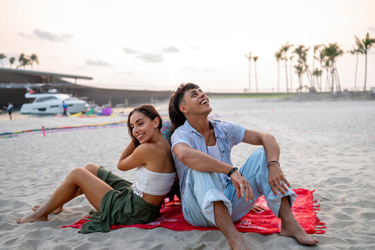 Happy young friends laughing together on a sandy beach during a sunny summer vacation