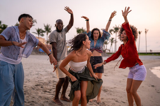 A diverse group of multicultural friends enjoying summer moments on the beach, dancing, laughing