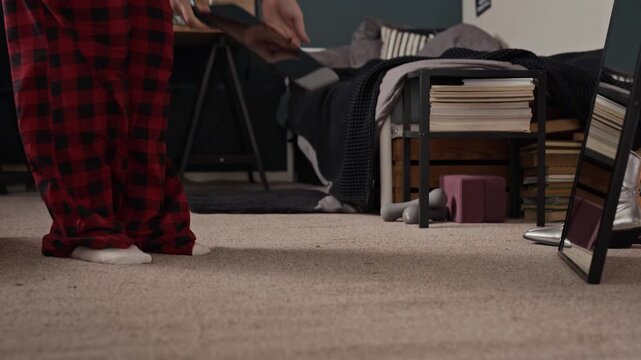 Young adult woman in pajamas pulling out digital scale from under bed and stepping on it to weigh herself. Footage suitable for wellness, fitness, and weight loss marketing campaigns