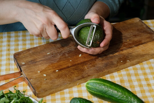 Food prep. Woman peeling avocado for making summer salad
