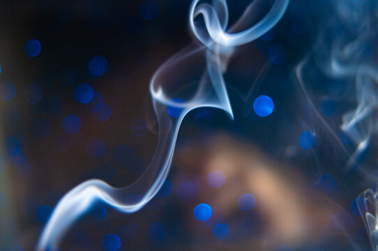 Deep blue lights and blurred white smoke swirl together in an abstract scene