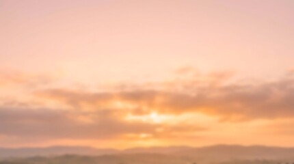 Fototapeta premium A breathtaking sunrise paints the sky with soft pink, orange, and yellow hues over a serene, misty landscape of rolling hills.