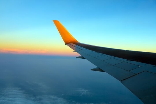 飛行機の窓から見る上空の夕焼けと主翼