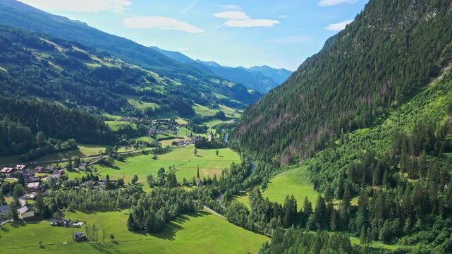 Village in green alpine valley surrounded by forested mountains