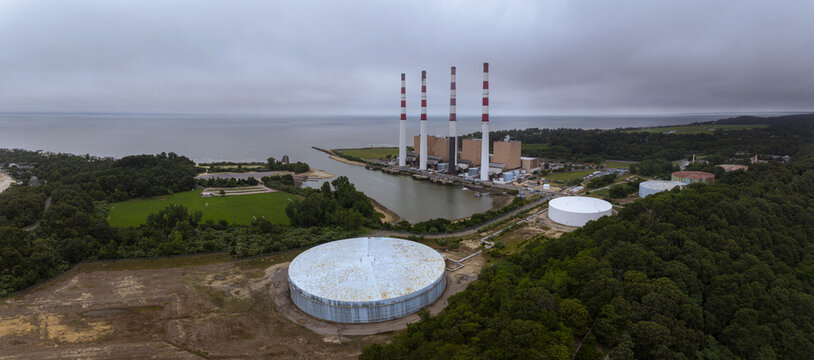 Aerial view of the Northport Power Station featuring four tall smokestacks and large storage tanks situated along the waterfront in Northport, New York, United States.