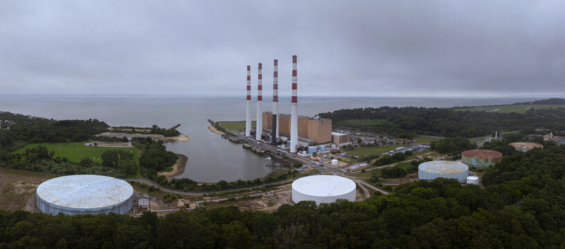 Aerial view of the Northport Power Station with its four iconic smokestacks, large storage tanks, and coastal infrastructure situated along the shoreline in Northport, New York, United States.