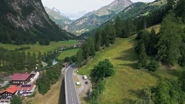 Aerial view of mountain road through green valley and village