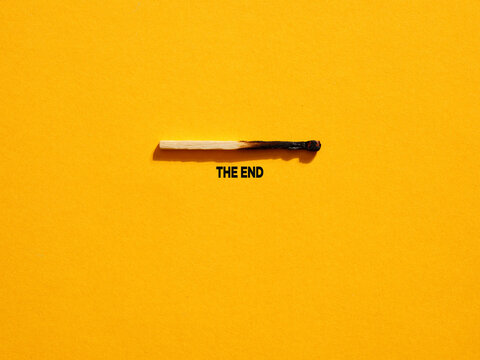 Burnt match lying on yellow background with the end writing