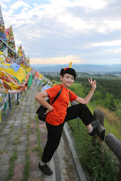 Historical monument Datsan Rinpoche Bagsha on Bald Mountain, buddist temple, landmark, sight. Tourist child, kid, cute boy in Buryat traditional national costume, hat. Buryat architecture in Ulan-Ude
