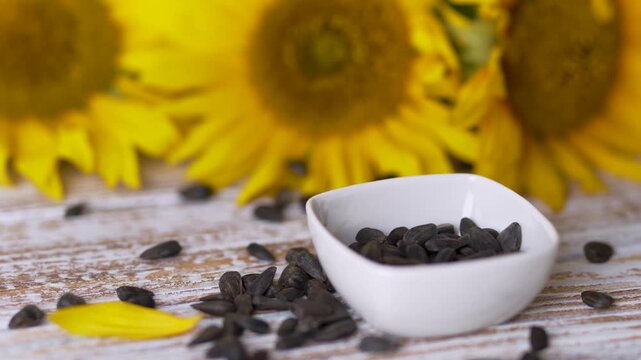 Pouring sunflower seeds with spoon into a white ceramic dish clip