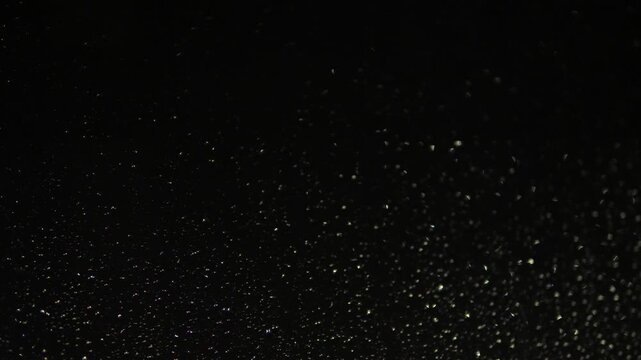 Small raindrops cover the transparent glass surface and shimmer beautifully in a dark space. Soft side lighting creates a deep night sky effect and a calm melancholic atmosphere