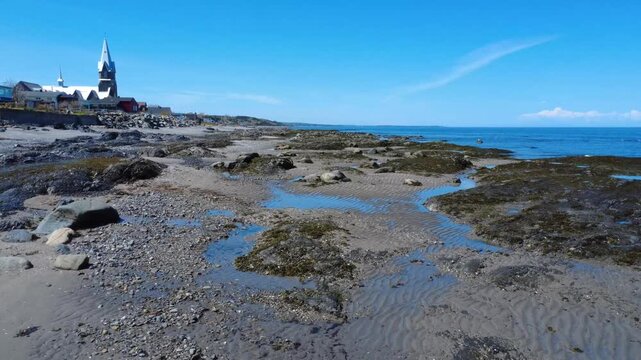 The iconic church watches over Baie-des-Sables and its exposed intertidal landscape.