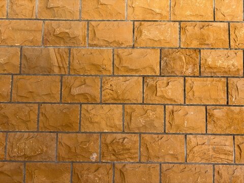 Golden yellow sandstone block wall texture with chiseled stone masonry blocks