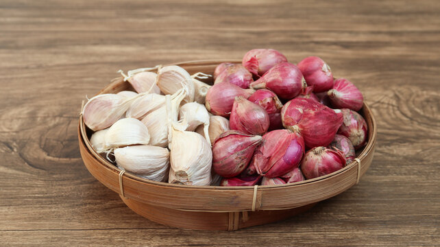 Garlic cloves and red onion or shallots on woven bamboo plate