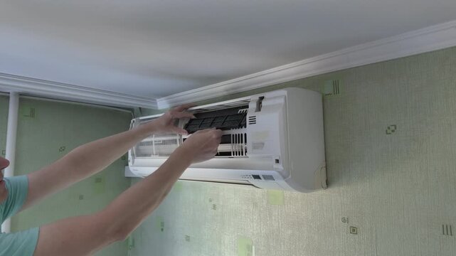 Technician removing air filter frame from split system air conditioner during home maintenance