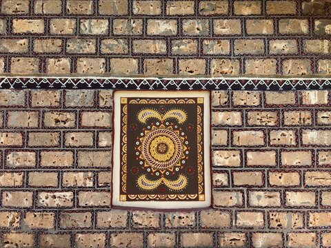 Decorative brick wall featuring traditional Kutchi Lippan mud art frame background close up photo