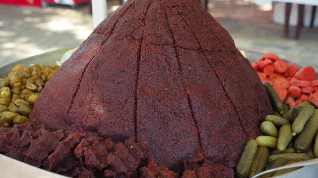 Traditional Turkish tomato paste displayed in a large cone shape with pickled vegetables at a local open air market food stall. High quality 4k footage