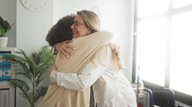 Middle age woman patient hugs doctor with stethoscope, arms wrapped around shoulders in clinic; comfort empathy support.