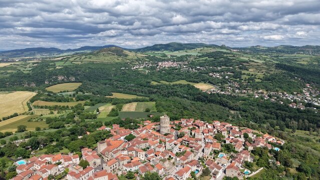 Aerial view of the historic village of Montpeyroux with its medieval tower, stone rooftops, and surrounding lush green landscape in Montpeyroux, Auvergne-Rhone-Alpes, France.