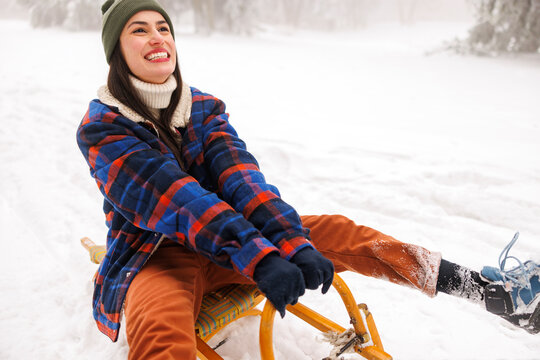 Man pulling woman on sledge while on winter vacation