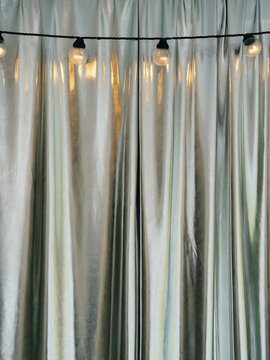 A garland of warm-lit bulbs against a silvery space-age fabric backdrop. Event concept.