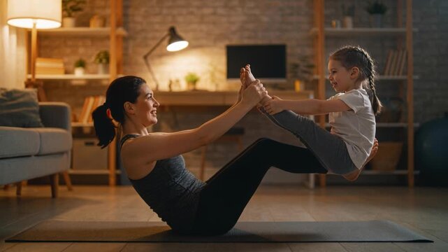 Reaching mom-daughter holding feet, balancing V-sit on dark mat for play, mom tank, child tee