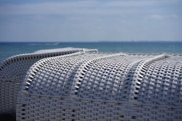 Fototapeta premium Nahaufnahme von weißen Strandkörben am Ostseestrand mit Blick auf das Meer in der Lübecker Bucht