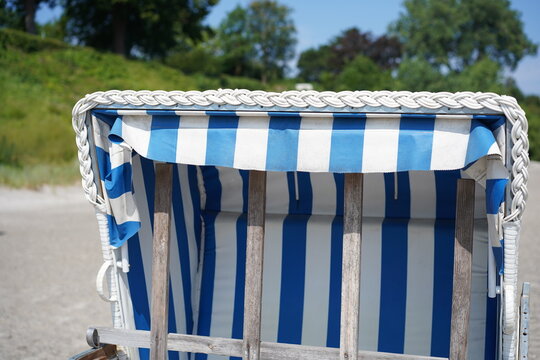 Nahaufnahme eines blau-wei&szlig; gestreiften Strandkorbs mit geflochtenem Zopfmuster an der Ostsee in der L&uuml;becker Bucht bei Sierksdorf
