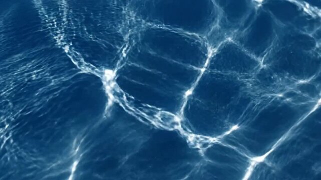 Mesmerizing close-up shot of water surface with light reflections dancing across a deep blue backdrop