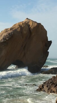 Vertical 4K 50fps real-time footage of Atlantic ocean waves crashing against the iconic Penedo do Guincho rock formation in Santa Cruz, Portugal