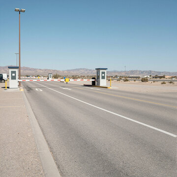 desert border crossing with closed gate and empty road on a sunny day symbolizing isolation and travel