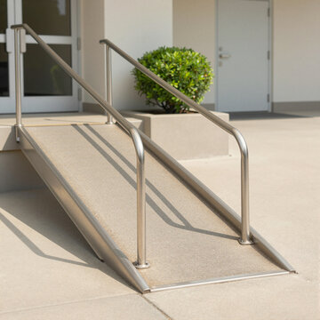 accessible entrance ramp with metal rails leading up to a modern building on a bright sunny day