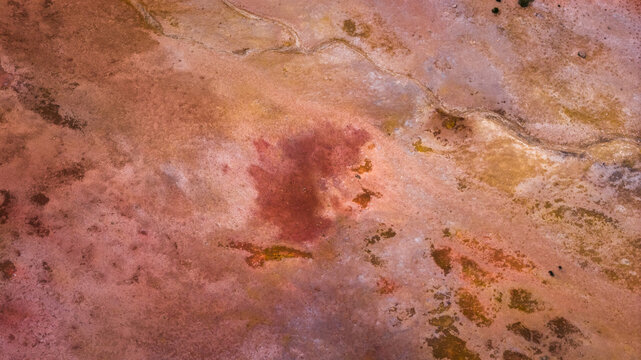 Aerial view of geothermal landscape with vibrant red and brown mineral deposits and textured earth patterns in Husavik, Nordurthing, Iceland.