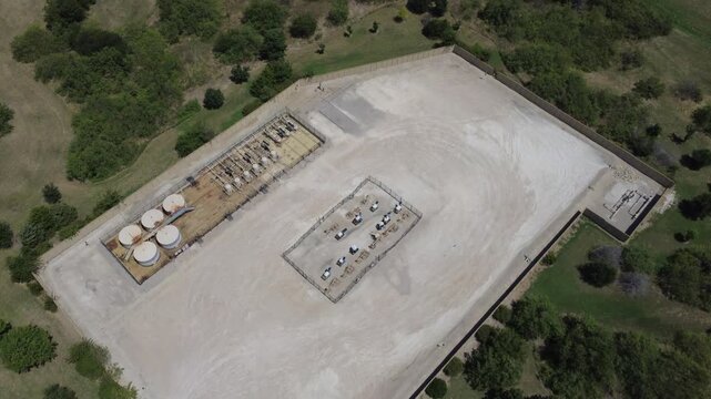 Industrial installation surrounded by vegetation lies off NW Hillery St near Fort Worth. Overhead view shows storage vessels, wellheads in suburban setting of Burleson, Texas